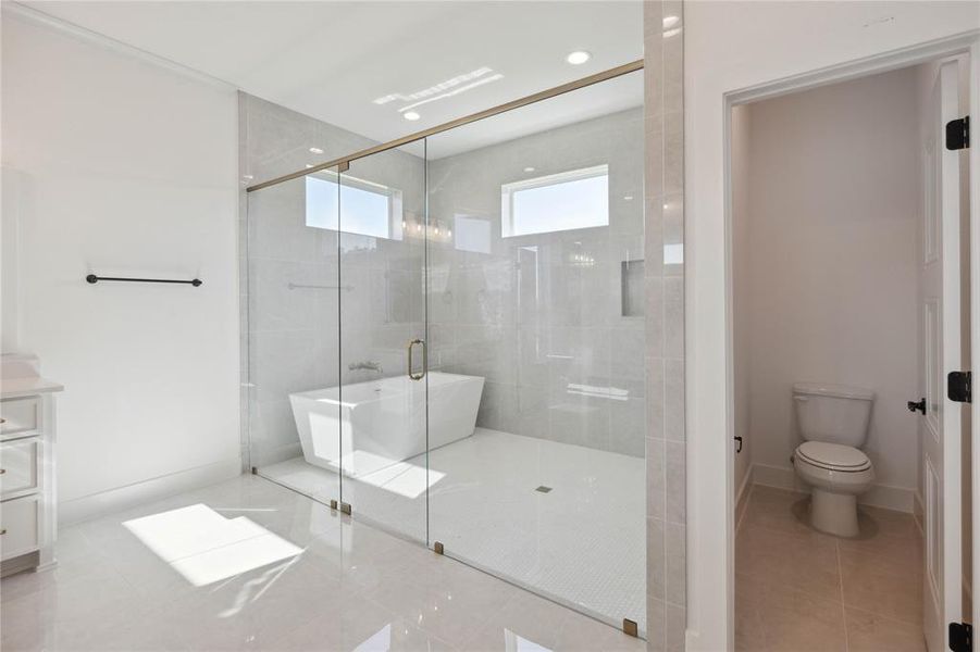 Full bathroom featuring toilet, vanity, tile patterned floors, and separate shower and tub