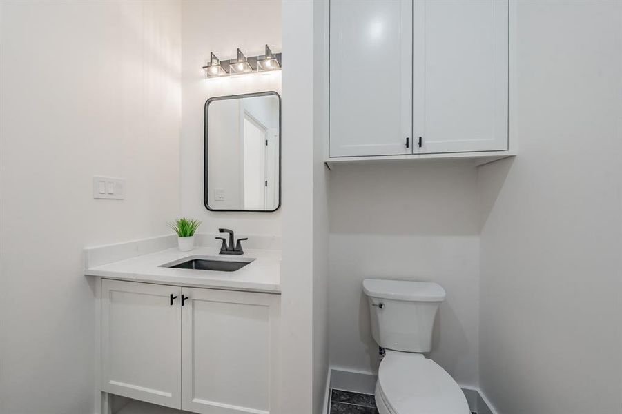 Guest Powder Room at foyer featuring vanity, toilet, and tile floors