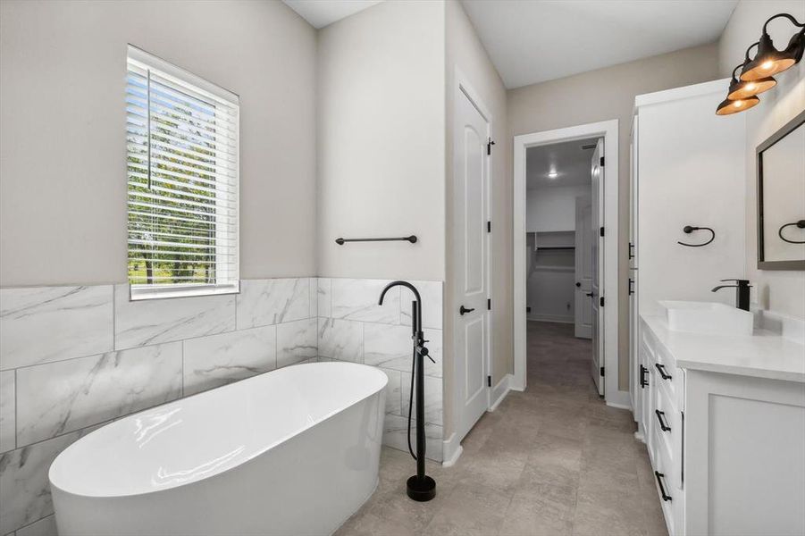 Bathroom featuring a tub to relax in, vanity, tile patterned floors, and tile walls