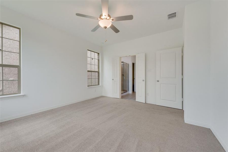 Empty room with ceiling fan and light colored carpet