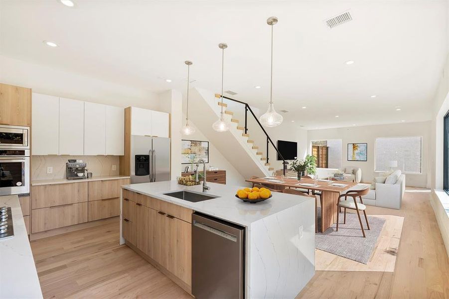 Kitchen with light hardwood / wood-style flooring, sink, stainless steel appliances, hanging light fixtures, and white cabinets