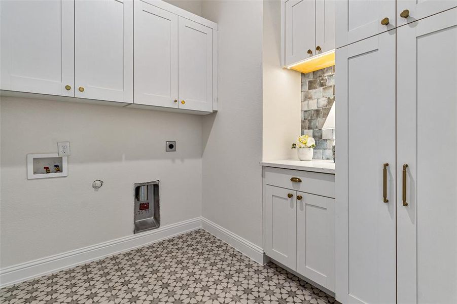 Clothes washing area with cabinets, hookup for an electric dryer, hookup for a gas dryer, and hookup for a washing machine