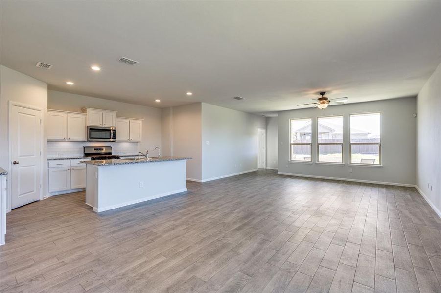 Kitchen featuring appliances with stainless steel finishes, light hardwood / wood-style flooring, an island with sink, and white cabinets