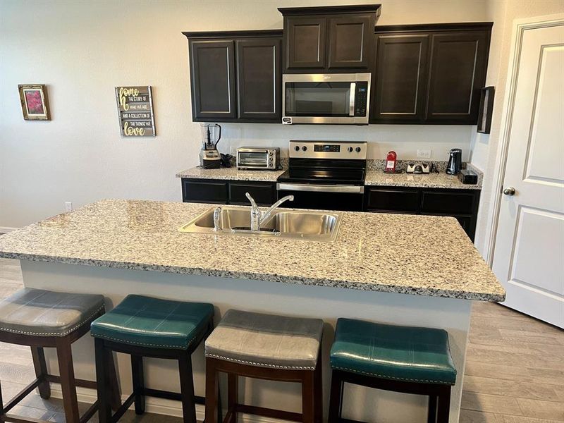 Kitchen with appliances with stainless steel finishes, light hardwood / wood-style floors, a breakfast bar area, and sink