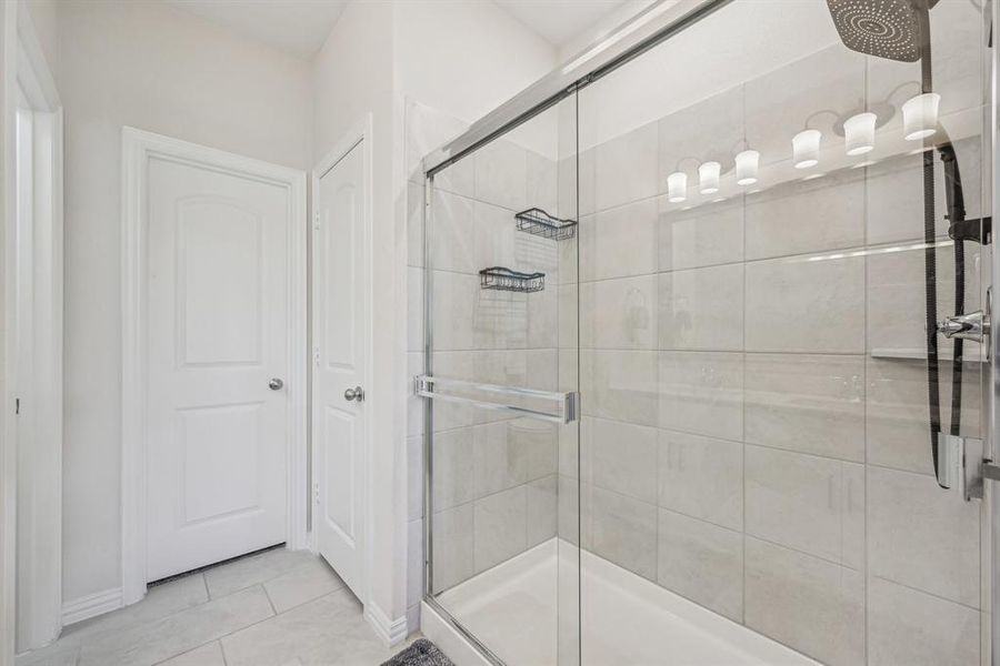 Bathroom featuring tile patterned flooring and a shower with door