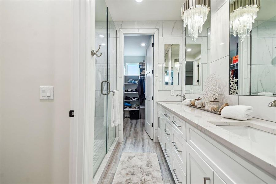 Primary bathroom featuring dual sinks, walk-in custom shower with dual shower heads and walk-in closet.