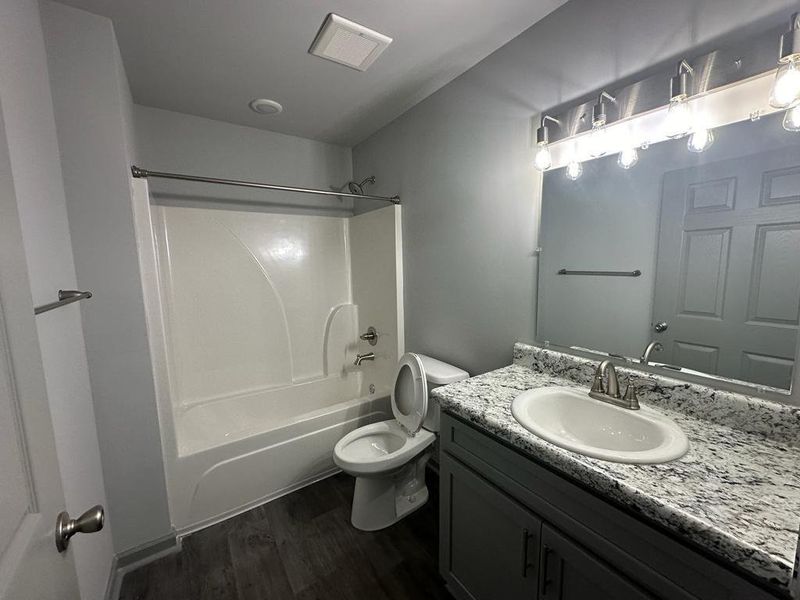 Full bathroom with shower / bathtub combination, toilet, vanity, and hardwood / wood-style flooring