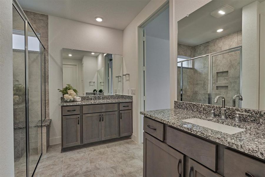 Lovely primary bathroom with double dual vanities, an oversized shower with floor-to-ceiling tile, and recessed lighting.