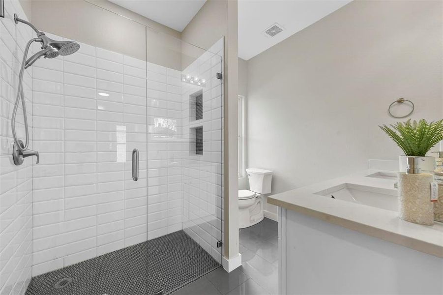 Bathroom with an enclosed shower, tile patterned floors, vanity, and toilet