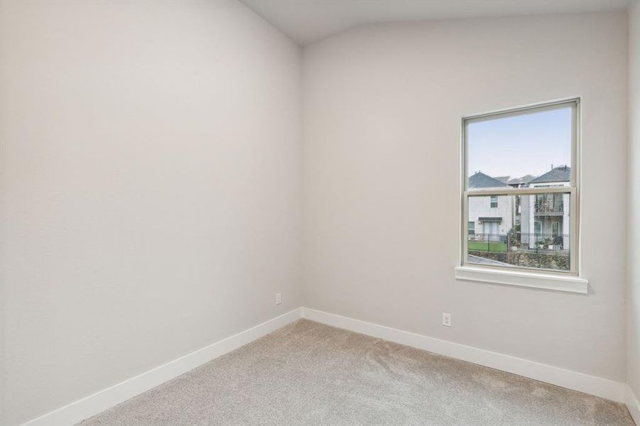 Carpeted empty room featuring lofted ceiling