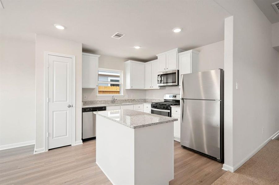 The charming kitchen has home owner favorite upgrades including dallas white granite, white cabintry, island, built in pantry, and stainless steel appliances.
