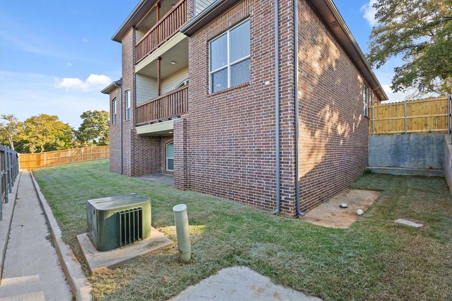 View of side of home with a yard and a balcony