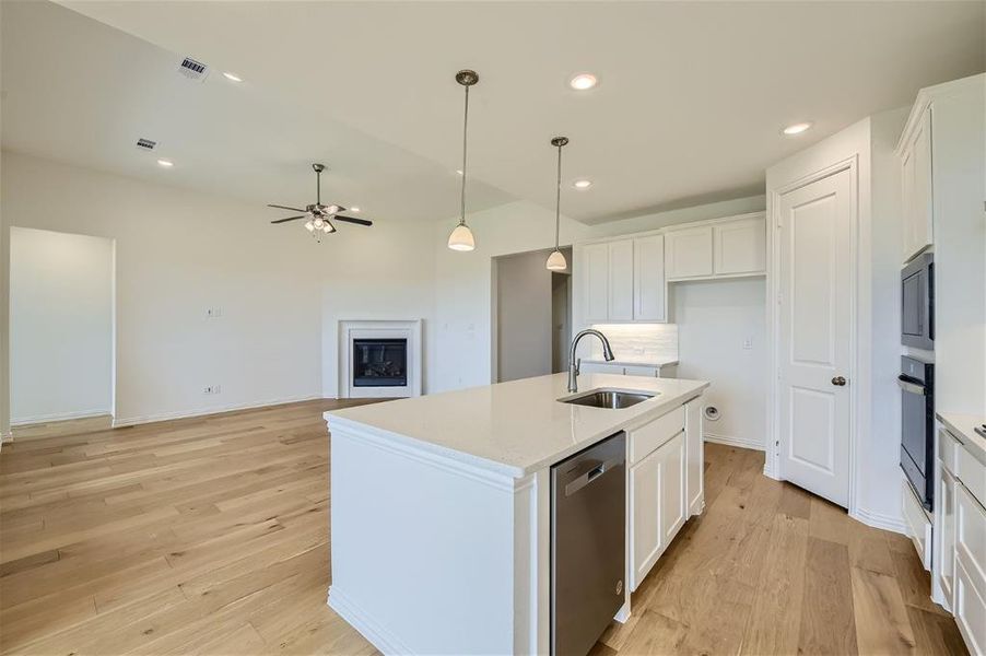 Kitchen featuring stainless steel appliances, a center island with sink, light wood-type flooring, sink, and white cabinets