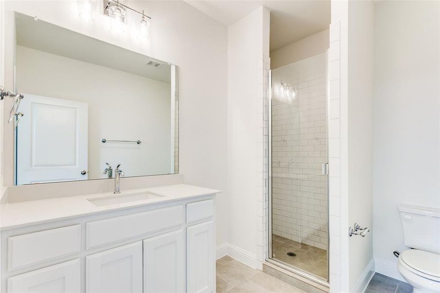 Bathroom with vanity, a shower with door, tile patterned flooring, and toilet