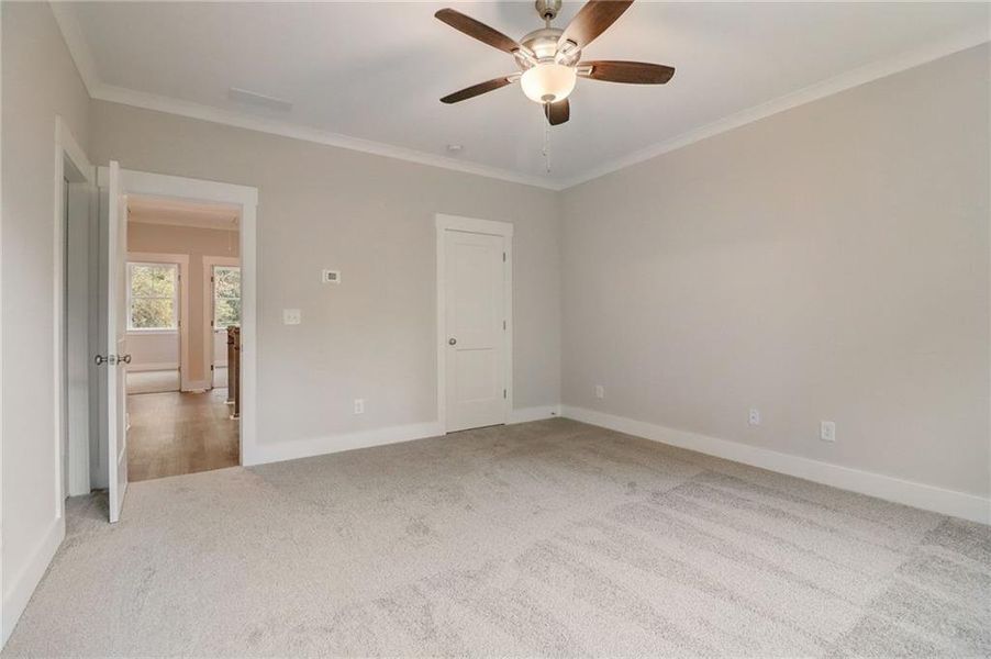 Empty room with ornamental molding, light carpet, and ceiling fan
