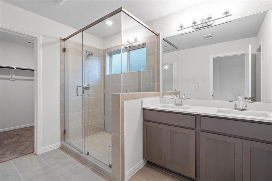 Indulge in luxury in the primary bathroom, featuring a spacious walk-in shower, dual vanities, and modern finishes. The thoughtful design combines style with functionality, offering a serene retreat where you can unwind after a long day. **This image is from another Saratoga Home with similar floor plan and finishes, not the Brayden floorplan.**