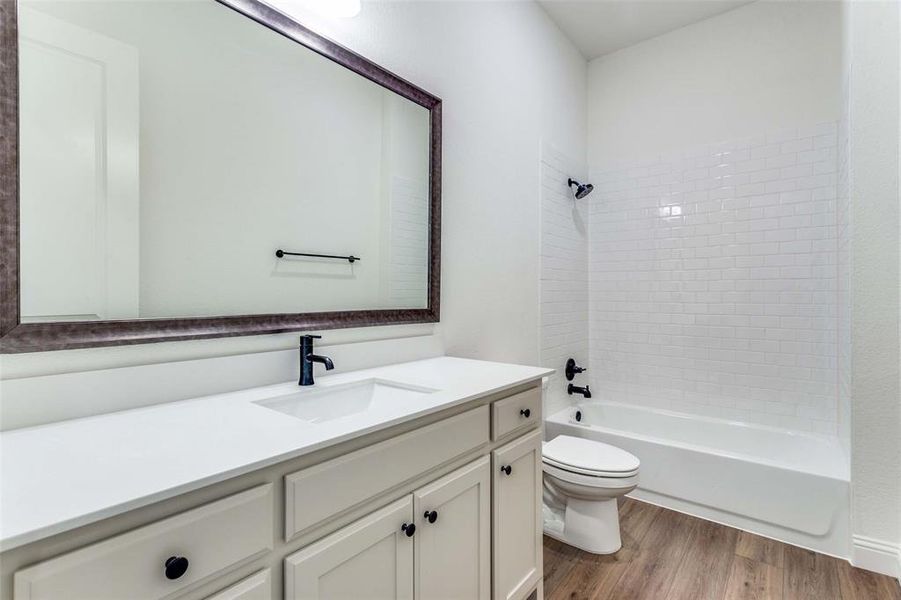 Full bathroom featuring toilet, vanity, wood-type flooring, and tiled shower / bath