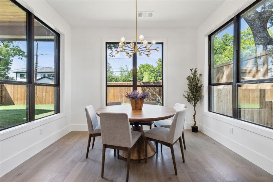 Dining area with hardwood / wood-style floors, an inviting chandelier, and a healthy amount of sunlight