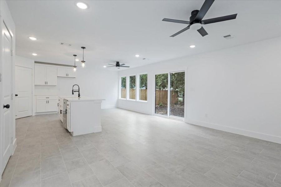 Kitchen with white cabinets, sink, ceiling fan, pendant lighting, and a kitchen island with sink