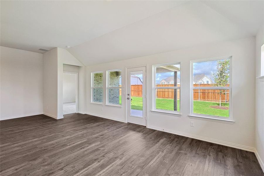 Empty room with dark wood-type flooring and vaulted ceiling