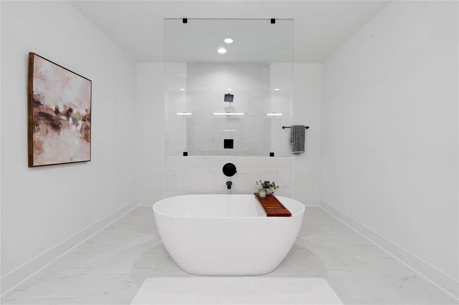 The primary bathroom showcases a stand-alone tub beside a sleek European-style walk-in shower, complete with a pony wall to ceiling glass panel