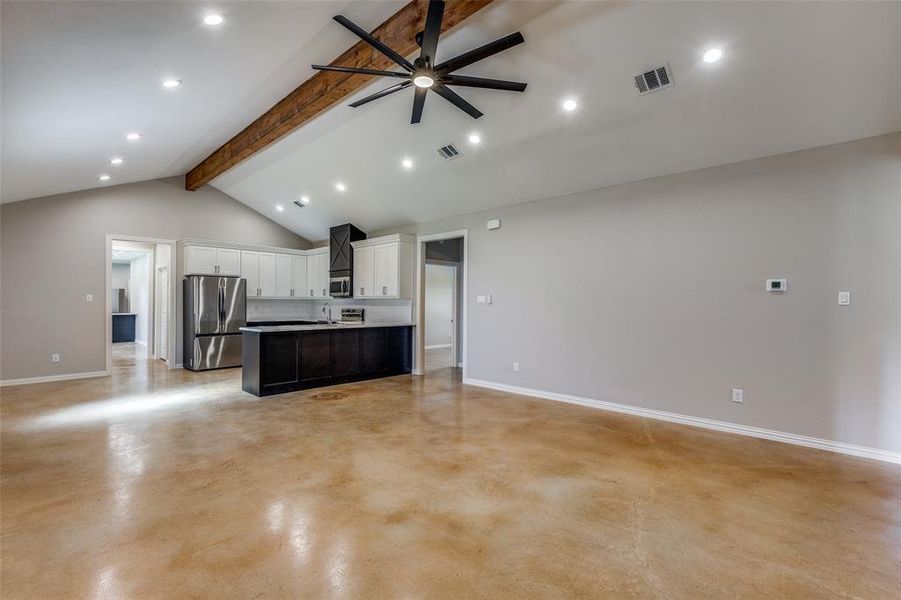 Large living area with vaulted ceiling. Doorway next to refrigerator leads to the secondary kitchen, 2 bdrms, 2 baths