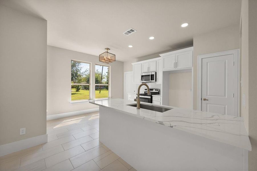 Kitchen with white cabinetry, stainless steel appliances, light stone countertops, and light tile patterned floors