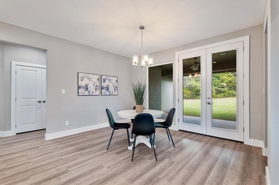 Dining space featuring light wood-type flooring, an inviting chandelier, and french doors