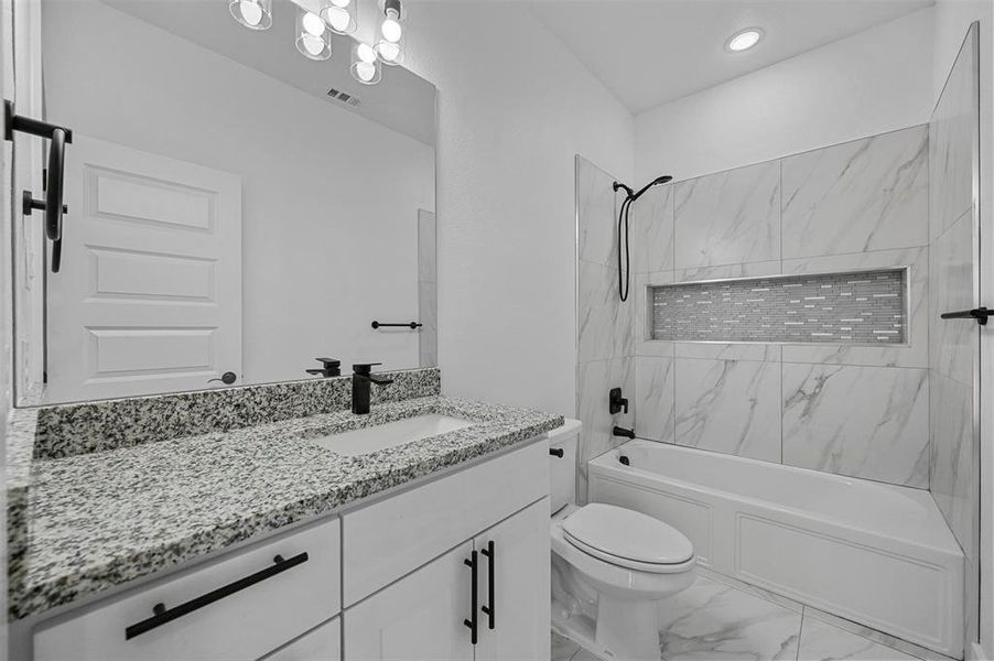 Full bathroom featuring vanity, tile patterned flooring, tiled shower / bath, and toilet