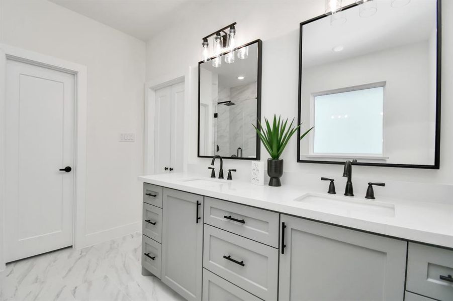 A sleek design with dual mirrors and separate sink over gray tone cabinets makes this ensuite timeless.