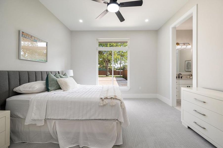 Carpeted bedroom featuring ceiling fan, sink, and ensuite bathroom