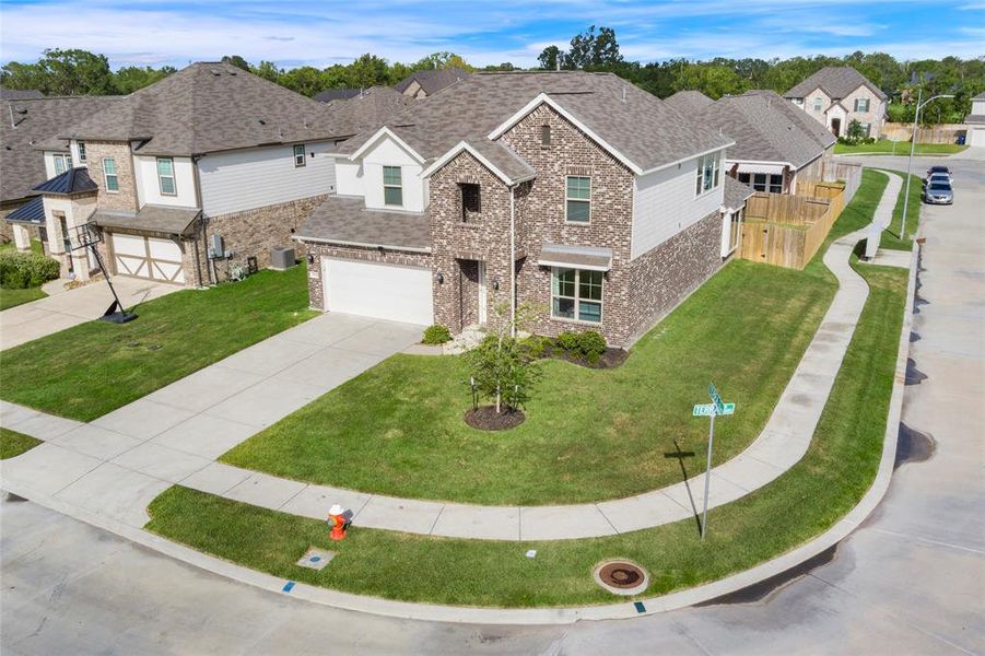 This is a two-story, corner-lot home with an attached two-car garage. The house is located in a well-kept suburban neighborhood with sidewalks and street lighting.