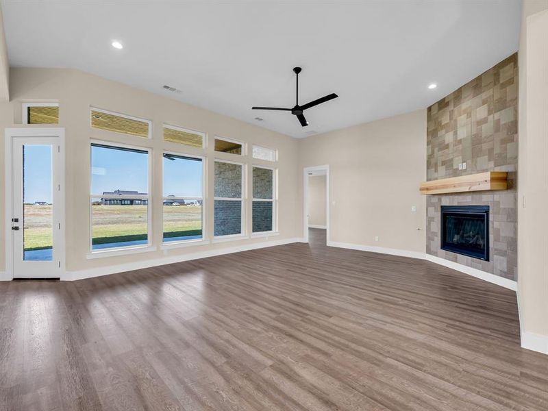 Unfurnished living room with ceiling fan, hardwood / wood-style flooring, and a fireplace