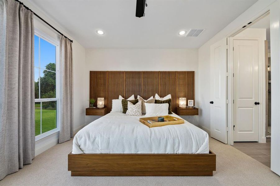 Main bedroom with light carpet and ceiling fan