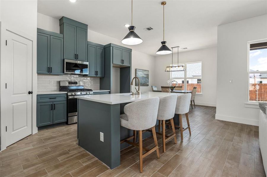 Kitchen featuring backsplash, appliances with stainless steel finishes, plenty of natural light, and pendant lighting