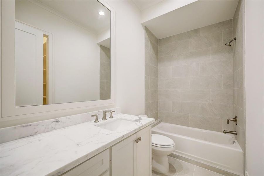 Another ensuite bath with tiled tub/shower combination, tile floor and gorgeous marble countertop and framed mirror!