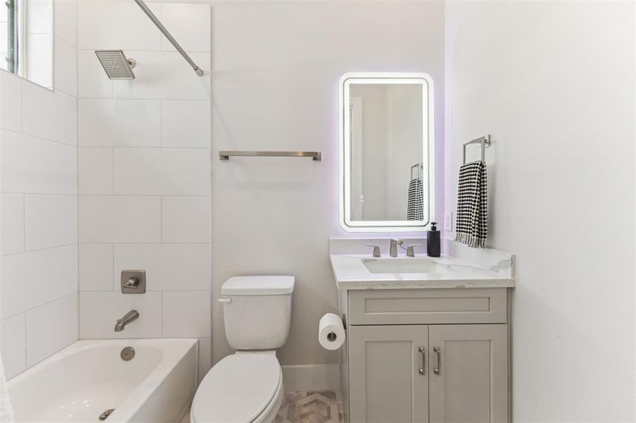 First floor bathroom features a quartz topped vanity and a tub/shower combo.