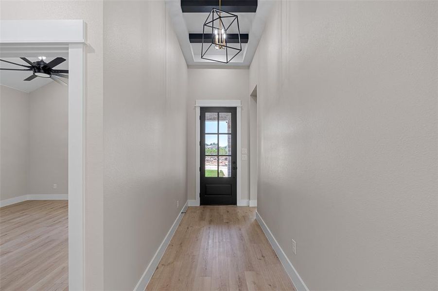 Entryway with ceiling fan with notable chandelier and light hardwood / wood-style floors