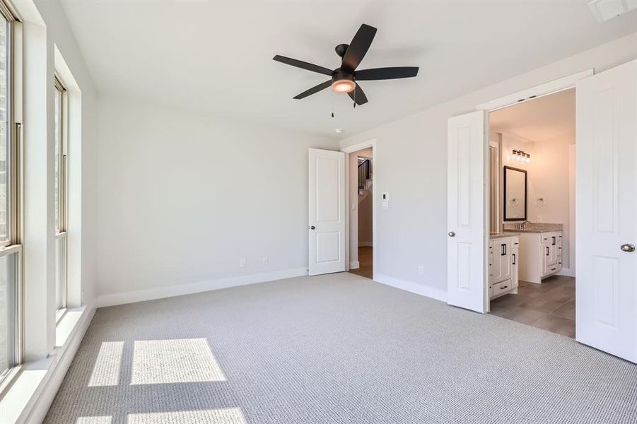 Unfurnished bedroom featuring light carpet, connected bathroom, sink, and ceiling fan