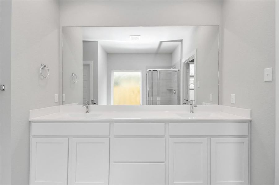 Enjoy a walk-in shower with tile surround, a separate garden tub with custom detailing, and an elegant vanity featuring light countertops, modern hardware, and bright recessed lights