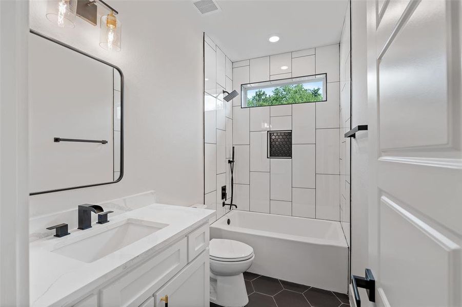 Full bathroom with tiled shower / bath, vanity, toilet, and tile patterned floors