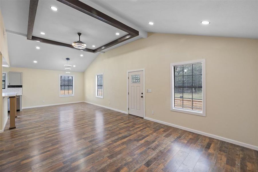 Unfurnished living room with beam ceiling, ceiling fan, hardwood / wood-style floors, and high vaulted ceiling