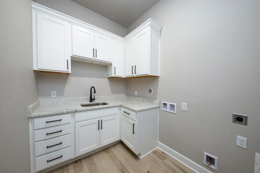 The laundry room in this home makes you want to do laundry.  Upper and lower cabinets with a built in sink provide stylish storage.