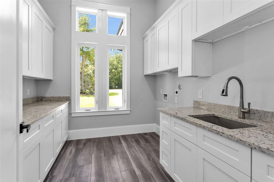 The large Utility Room features casement windows allowing fresh air and sunlight, along with a large sink area, and an incredible amount of counter space and cabinets.