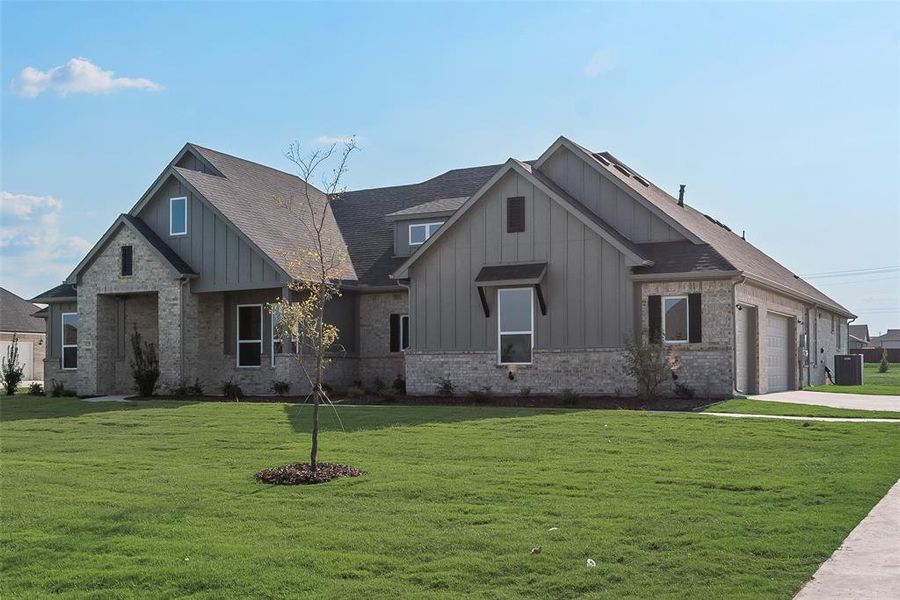 View of front facade featuring central AC, a front yard, and a garage