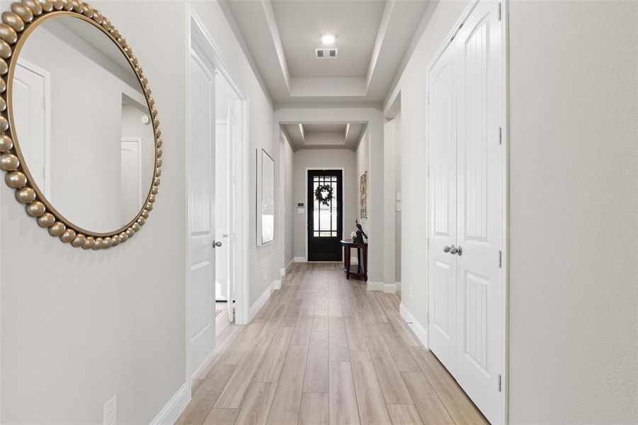 Discover the refined charm of this home, boasting luxurious vinyl plank floors and sophisticated tray ceilings throughout the inviting foyer and primary bedroom areas.