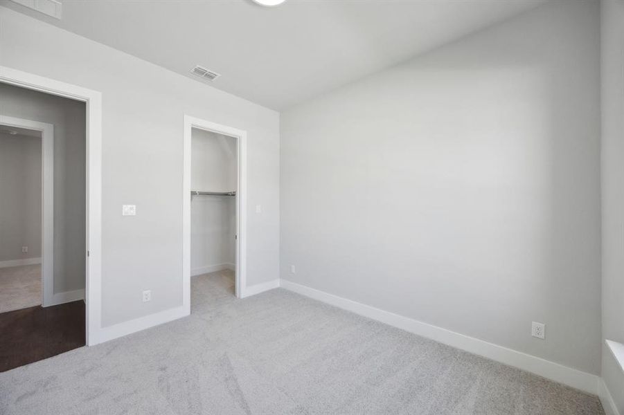 Unfurnished bedroom with carpet flooring, a closet, and a walk in closet