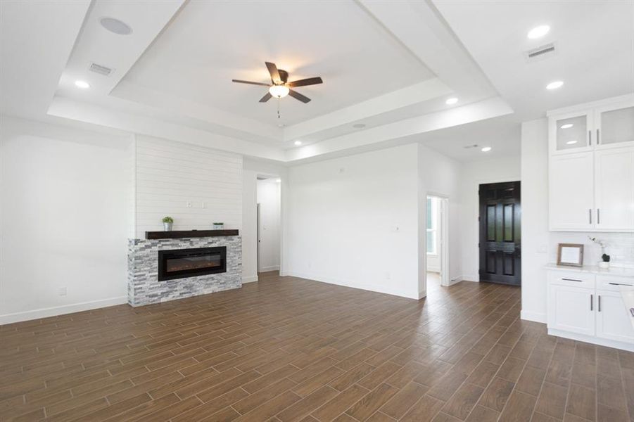 Spacious living area with high tiered ceilings, ceiling fan, recessed lighting, tile flooring, and modern fireplace.  The living area includes a BLUETOOTH AUDIO SOUND SYSTEM for entertaining.