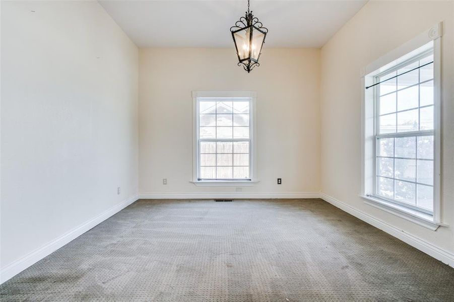 Unfurnished room with plenty of natural light, carpet, and an inviting chandelier