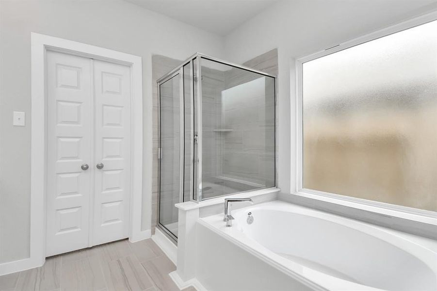 This additional view of the primary bath features a walk-in shower with the tile surround and separate garden tub perfect for soaking after a long day.